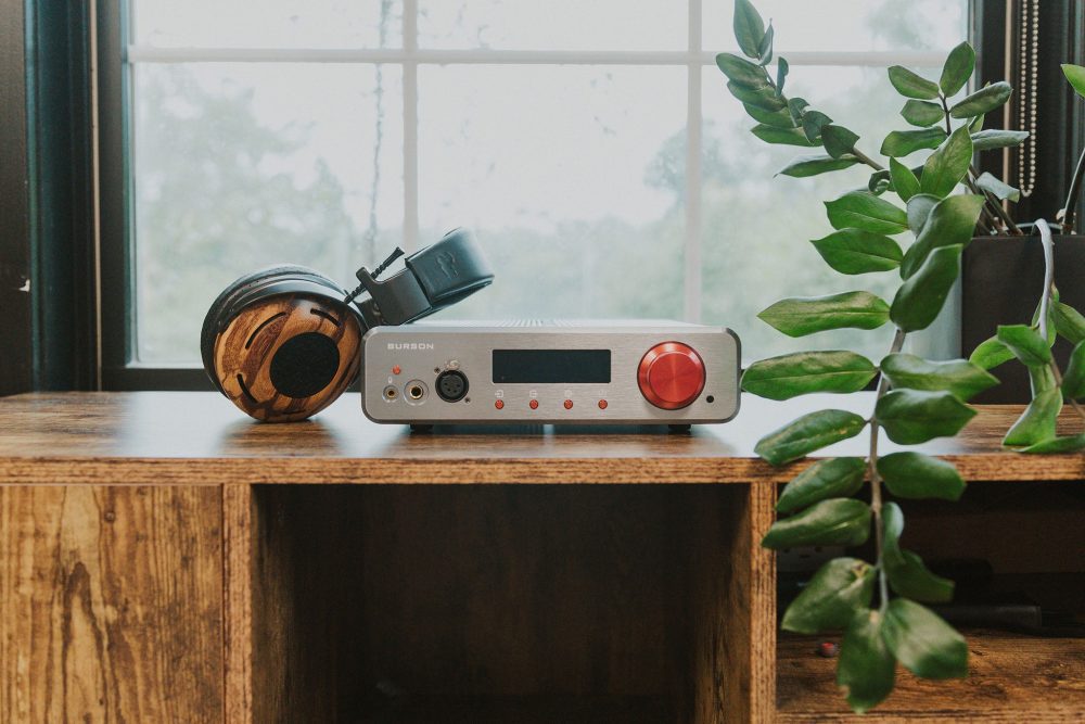 Burson soloist 3x grand tourer sitting on wooden table with headphone leaning on left side