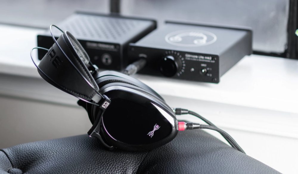 Dan Clark Noire X headphone on black leather couch with Headamp amplifiers in background Bokeh