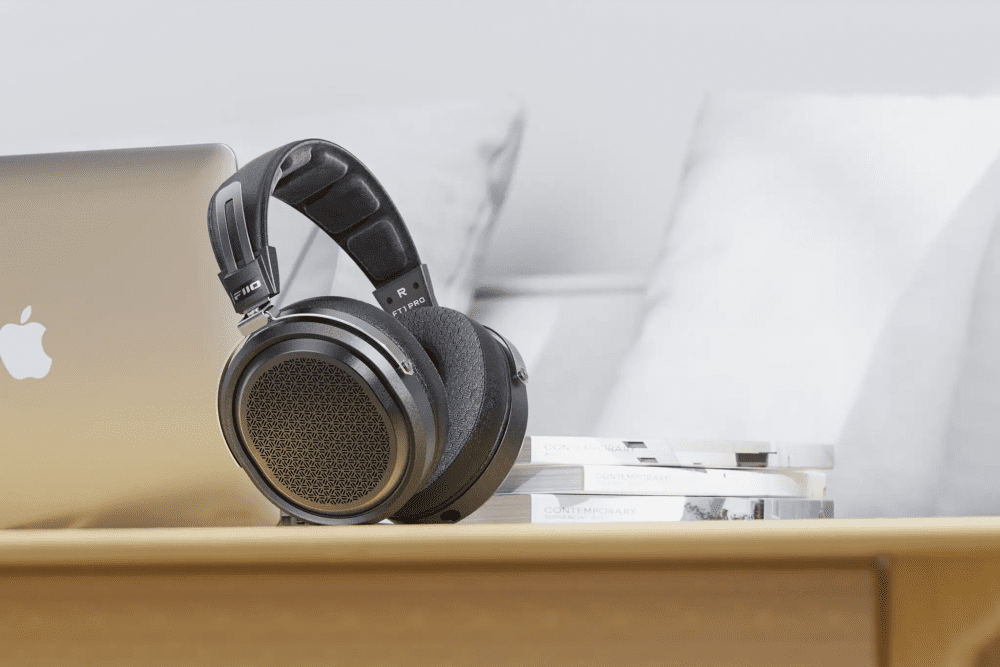 FiiO FT1 Pro headphones sitting on wooden table with stack of books and laptop