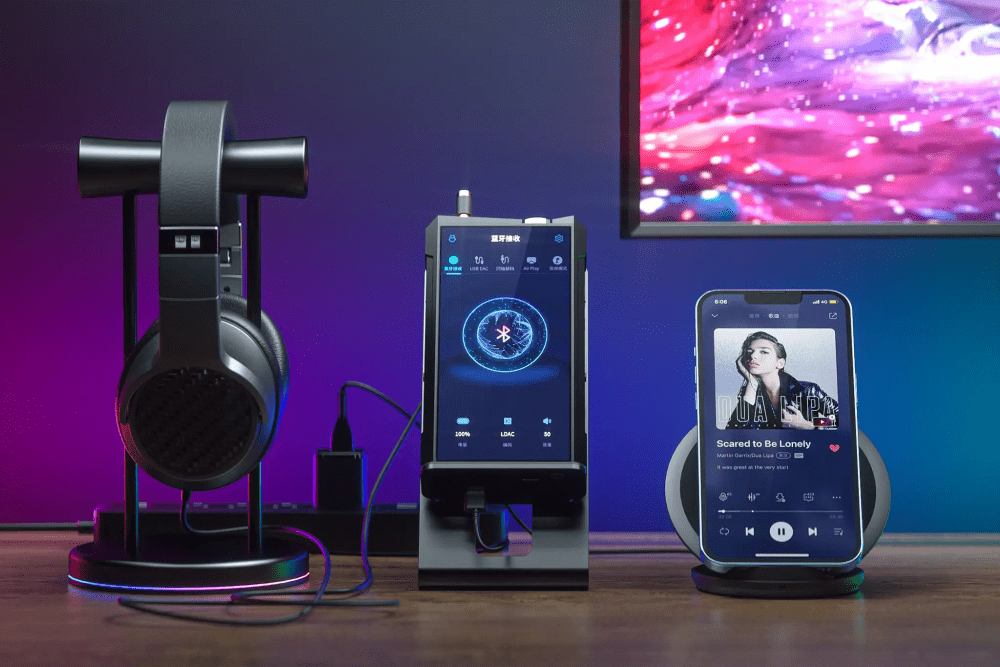 FiiO M17 DAP sitting on cooling stand on wooden table with iphone and headphone on stand