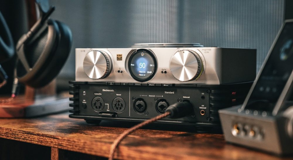 iFi iCAN Phantom front 3 quarter with connected Meze Audio cable and headphones on wood table