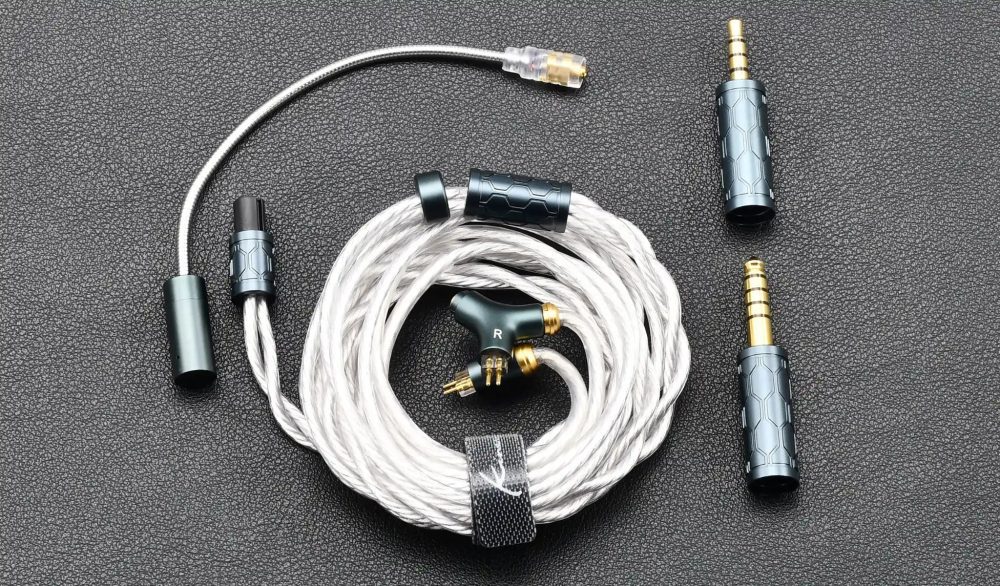 Kinera Gramr Pro coiled cable with all accessories over gray leather fabric bird's eye