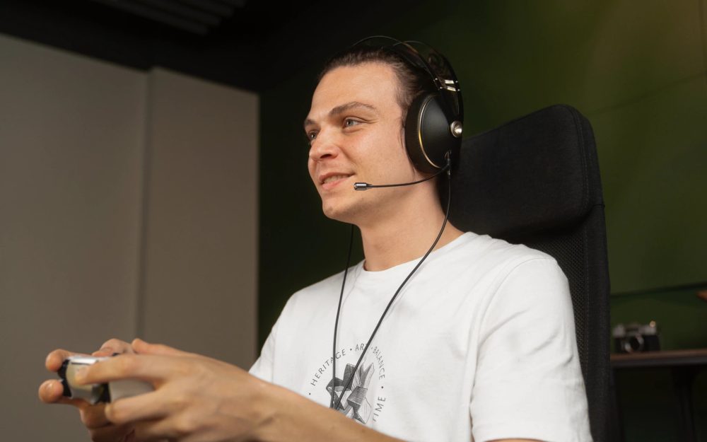 human wearing Meze NEO with attached boom mic in gaming chair holding xBox controller