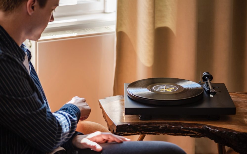 Pro-Ject Debut Carbon EVO dramatic warm on wood table with male operator