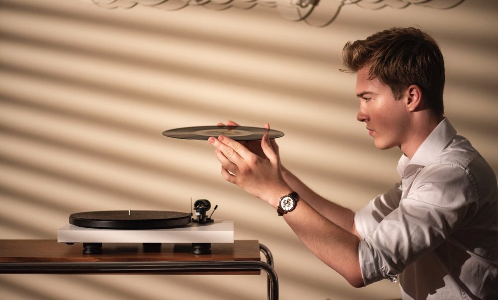 Pro-Ject Debut Carbon EVO white finish on desk warm dramatic with male operator holding record above turntable