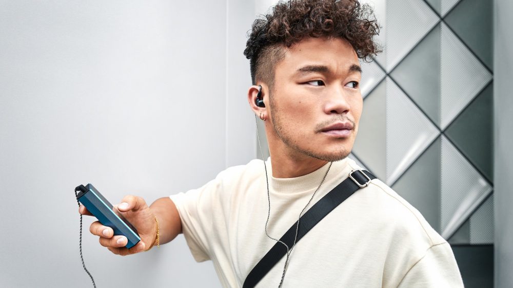 Audiophile wearing Sennheiser IE 200 earphones holding high-end digital player