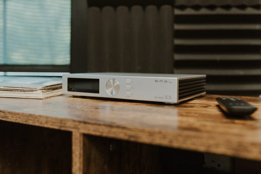 Small d400 ex dac sitting on wooden table with vinyl records