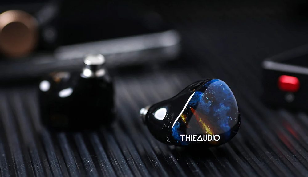 Thieaudio Origin earphones with music player Bokeh effect front left shell over black ribbed table