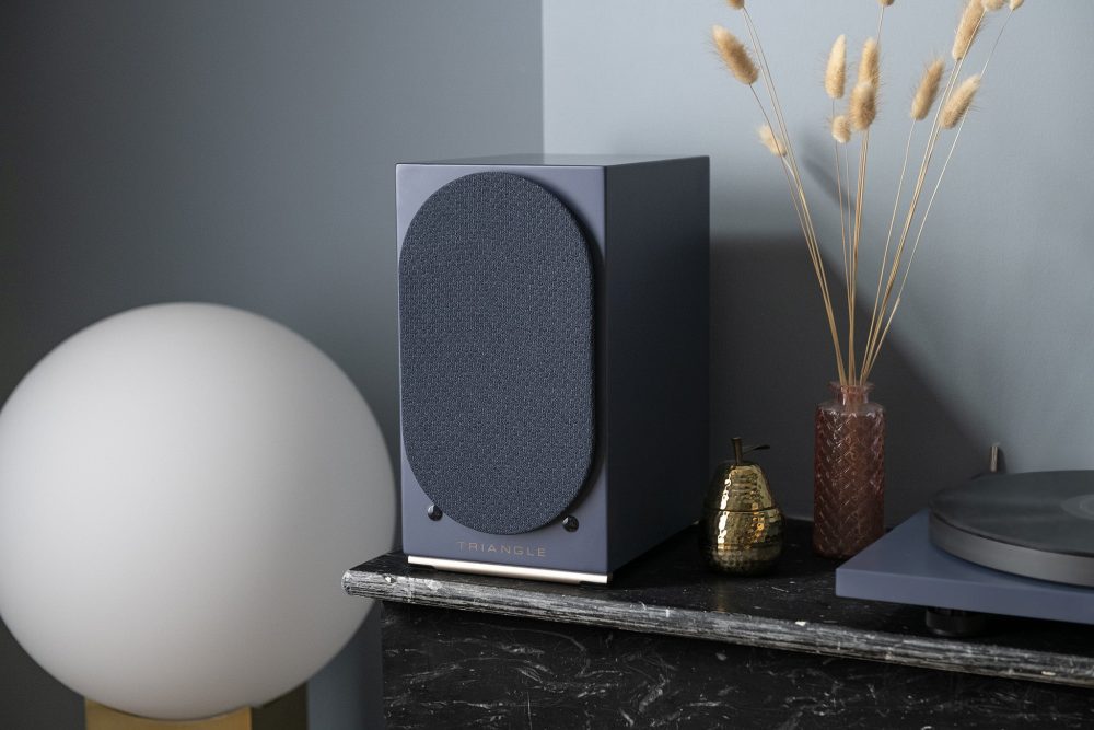 Triangle audio AIO twin speaker sitting on black marble table with plant and record player