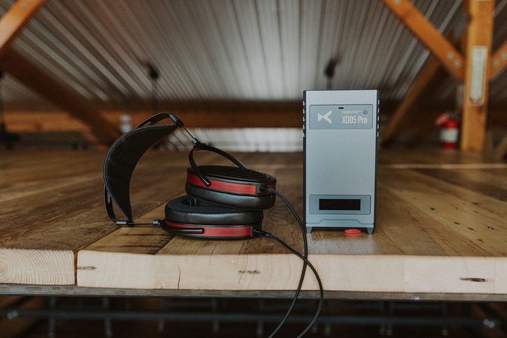 Xduoo xd05 pro sitting on wooden table next to hifiman Arya headphone